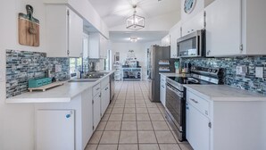 Une cuisine moderne avec des meubles blancs, un pare-feu en carrelage et des appareils électroménagers en acier inoxydable.