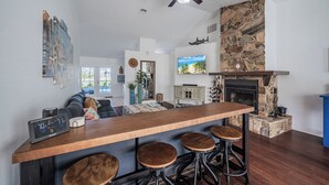 Une cuisine moderne avec un bar en bois, une cheminée en pierre et un ventilateur de plafond.
