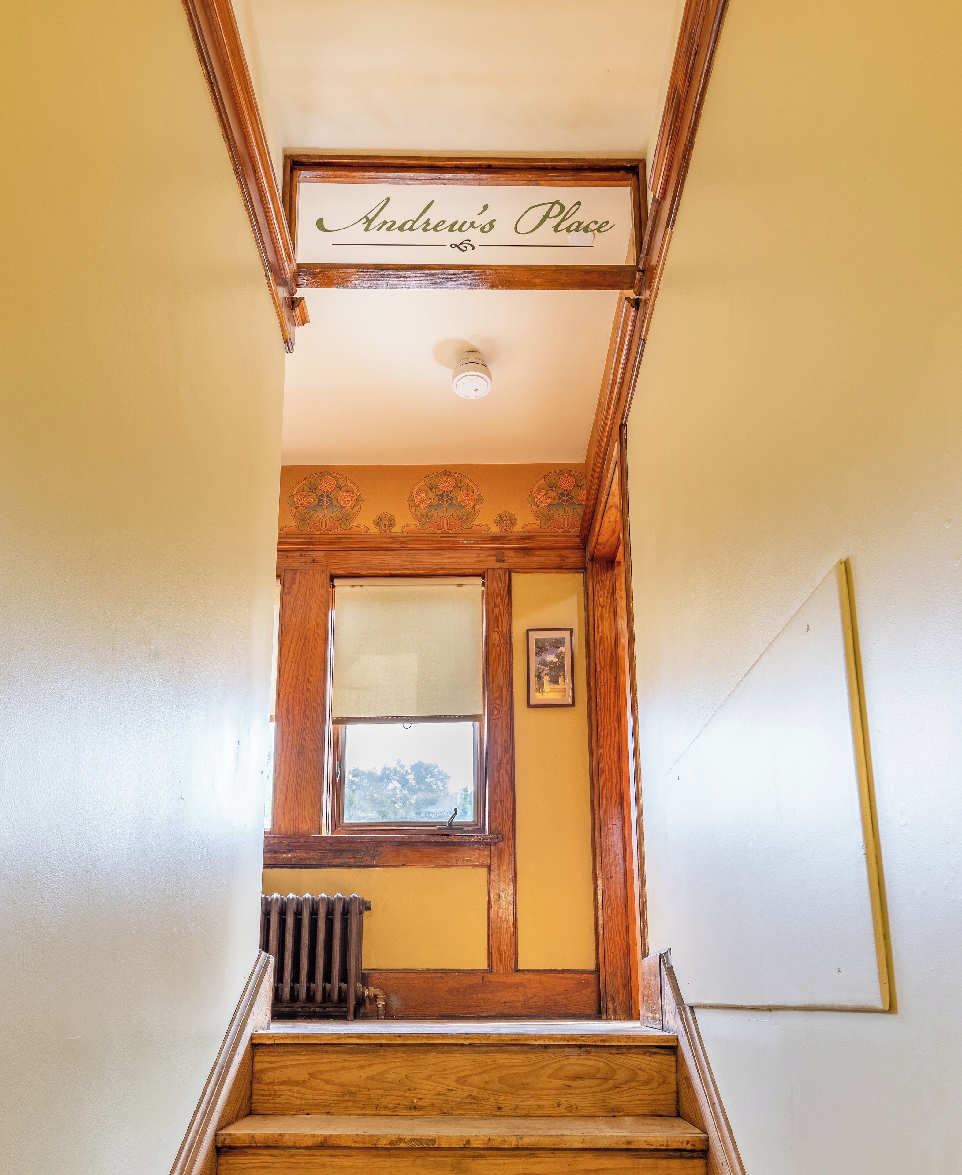 A staircase with a wooden handrail, a radiator, and a door with a window.