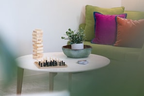 A round table with a wooden Jenga tower, a chessboard, and a plant in a ceramic pot.