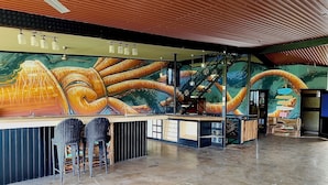 A bar area with a mural, bar stools, and a staircase. - CoCo Bongo Hostel (Bahia de Caraquez)