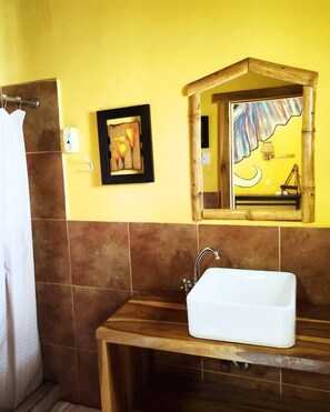 Ein Badezimmer mit einem Holzbac, einem Spiegel und einem gerahmten Bild an der Wand.