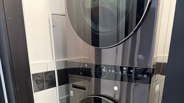 A compact, modern laundry room with a built-in washer and dryer, a small storage cabinet, and a tiled floor.
