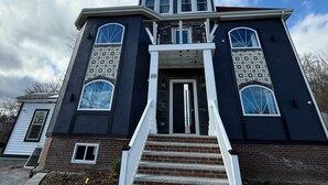 A two-story house with a central entrance, a brick foundation, and a large front yard.