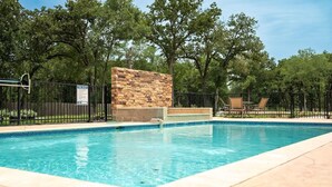 A swimming pool with a stone wall and a metal fence.