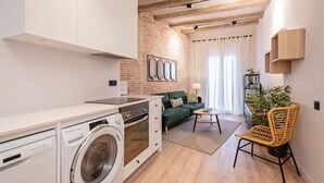 A modern apartment with a kitchen, a living area with a sofa, and a dining table.