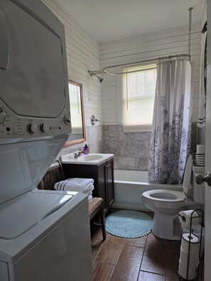 Een kleine badkamer met een ingebouwde wasmachine, toilet en douche.
