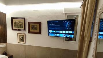 A hotel room with a bed, a TV mounted on the wall, and a mirror on the dresser.