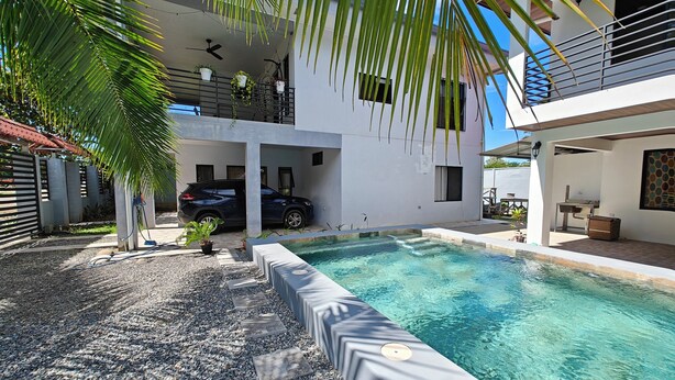A modern two-story house with a swimming pool, a covered carport, and a balcony with plants. - AJ House & Suites (Bahía Ballena)