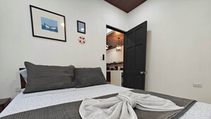A neatly made bed with a patterned bedspread, two dark pillows, and a towel on the bed. - AJ House & Suites (Bahía Ballena)