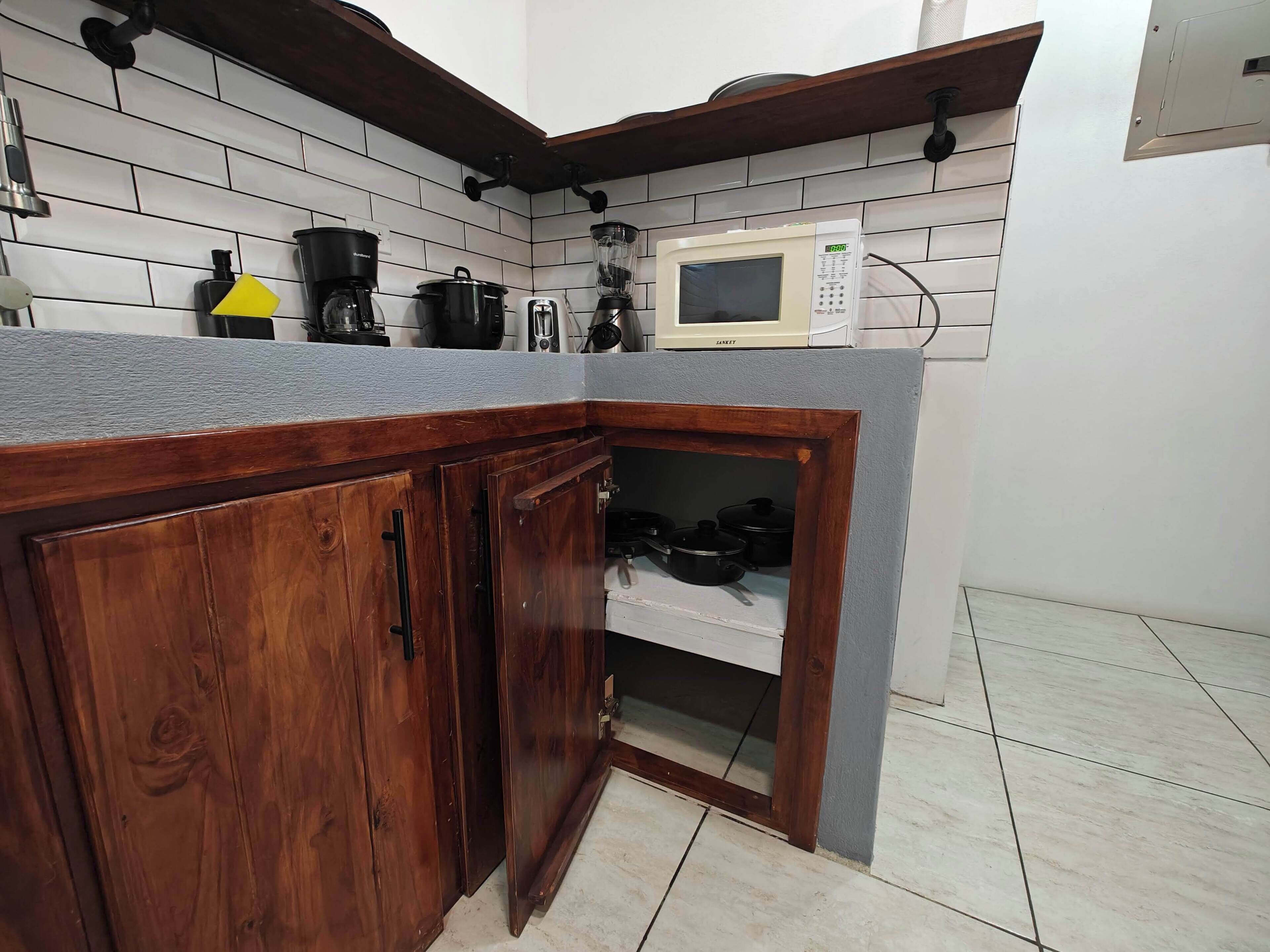 Una cocina con armarios de madera, microondas y cafetera.