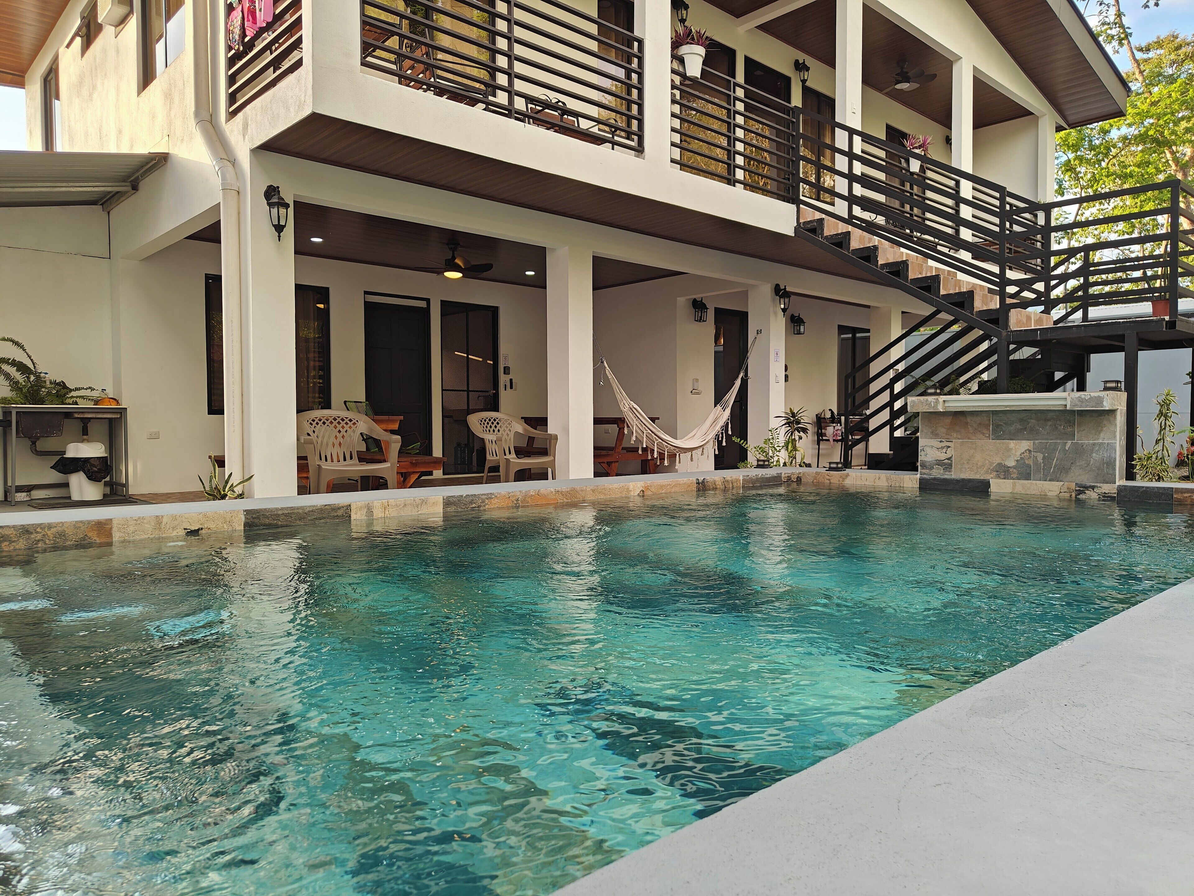 Une maison moderne dotée d’une piscine, de mobilier d’extérieur et d’un escalier menant à un balcon.