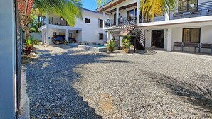 A modern building with a covered outdoor area, a pool, and a staircase leading to a balcony. - AJ House & Suites (Bahía Ballena)