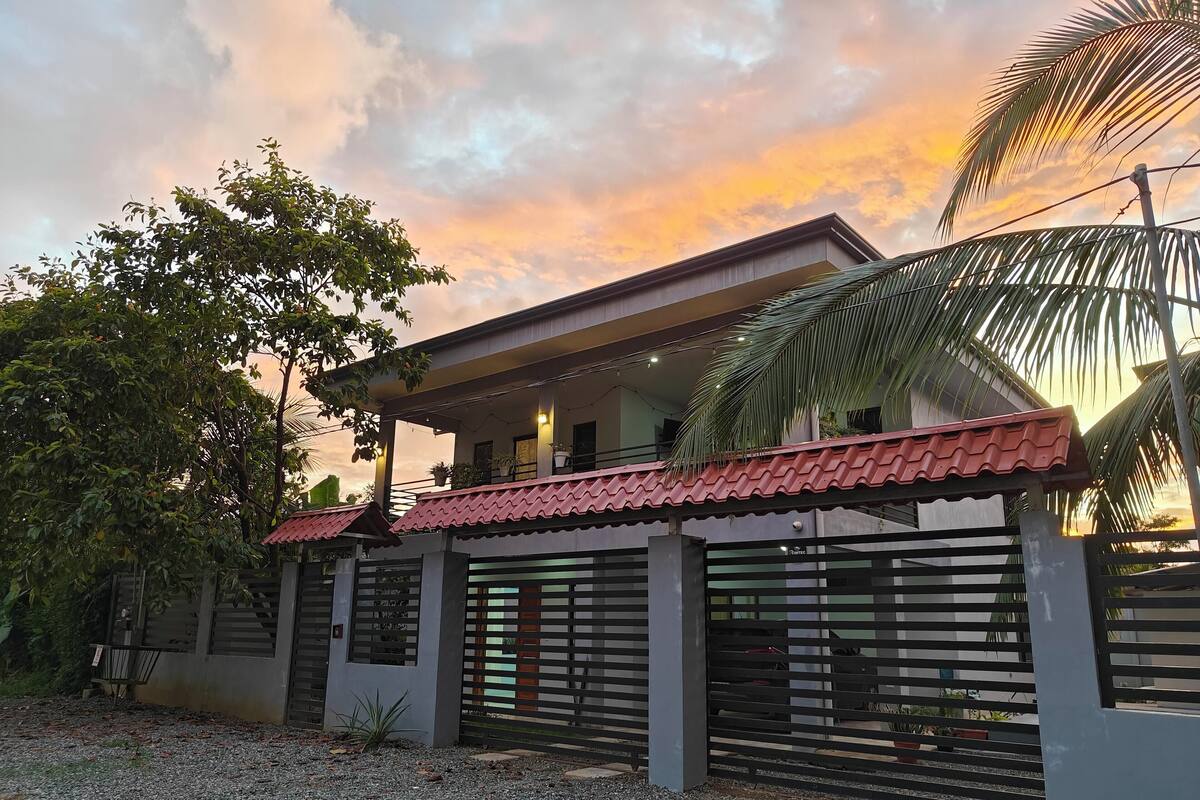 A modern house with a red roof, a balcony, and a gated entrance.
