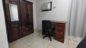 A room with a wooden wardrobe, a desk with a chair, a wall-mounted air conditioner, and a curtain. - AJ House & Suites (Bahía Ballena)