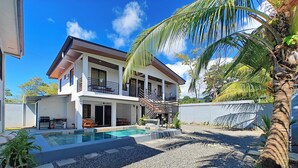 A two-story house with a swimming pool, outdoor seating, and a staircase leading to a balcony. - AJ House & Suites (Bahía Ballena)
