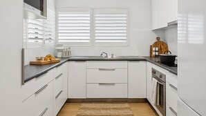 A modern kitchen with white cabinetry, a double sink, and a wooden cutting board with bread.