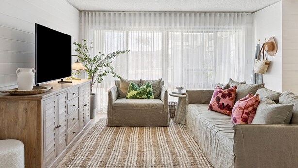 A living room with a sofa, a coffee table, a TV, and a plant.