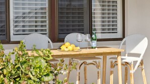 A wooden table with a plate of lemons and a bottle of beer, surrounded by wicker chairs.
