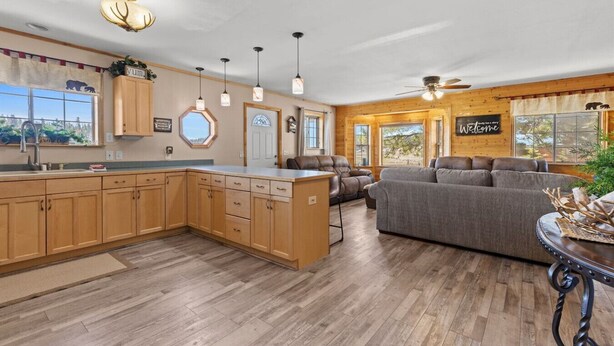 A spacious kitchen with wooden cabinets, a central island, and pendant lighting.