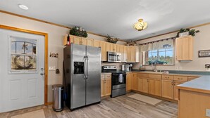 A modern kitchen with wooden cabinets, stainless steel appliances, and a window with a view.