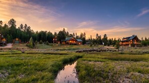 Eine am See gelegene Lodge mit mehreren Hütten, einem kleinen Bach und bewaldeter Landschaft im Hintergrund.