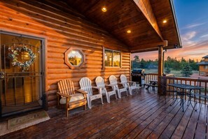 Una cabaña de madera con porche, mobiliario exterior y vista al bosque.