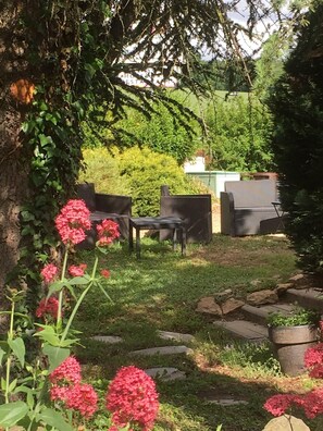 A garden area with a barbecue grill, outdoor furniture, and a pathway. - Balladins Lyon Est (Saint-Quentin-Fallavier)
