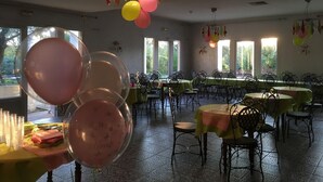 A dining area with tables and chairs, a chandelier, and balloons. - Balladins Lyon Est (Saint-Quentin-Fallavier)