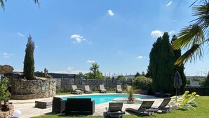 Une piscine avec des chaises longues et un mur en pierre.