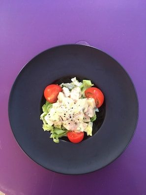 A black plate with a salad on a purple table. - Balladins Lyon Est (Saint-Quentin-Fallavier)