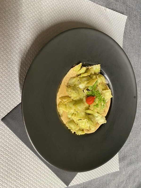 A round black plate with a salad on a textured white and gray tablecloth. - Balladins Lyon Est (Saint-Quentin-Fallavier)