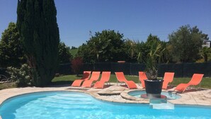 A swimming pool with a curved edge, surrounded by orange lounge chairs and a potted plant. - Balladins Lyon Est (Saint-Quentin-Fallavier)