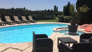 Une piscine avec des chaises longues et une plante en pot.