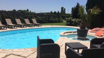 A swimming pool with lounge chairs and a potted plant.