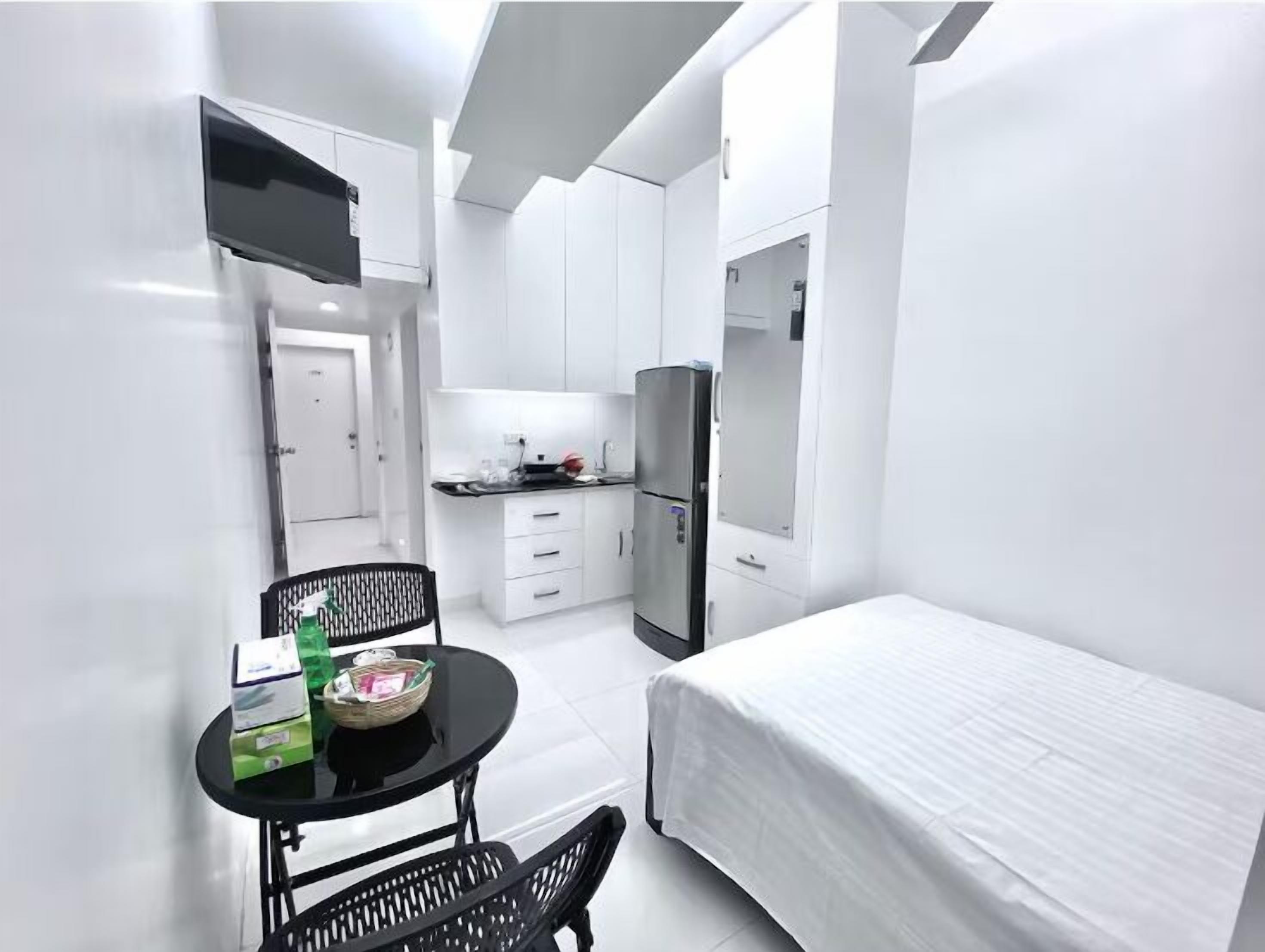 A compact, modern room with a kitchenette, a dining area with a table and chairs, and a bed.