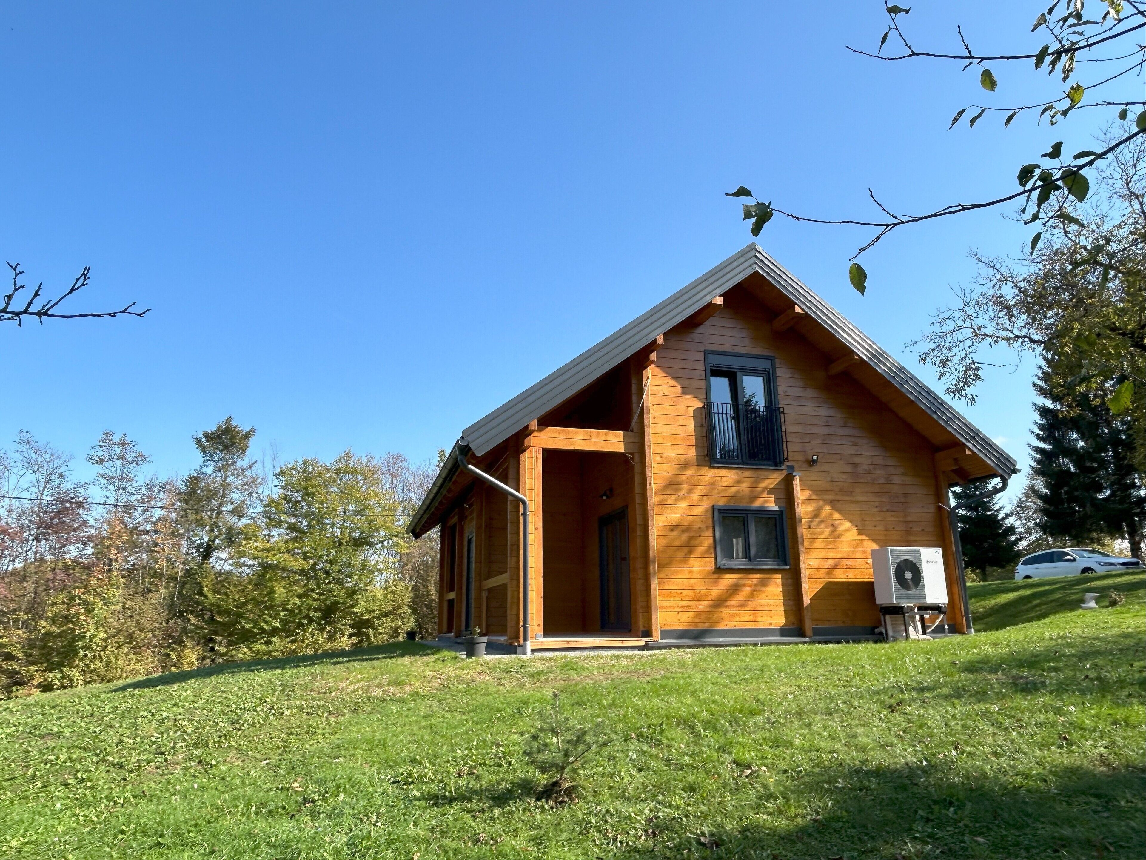 Une cabane en bois avec un toit à deux versants, un balcon et un appareil de climatisation.