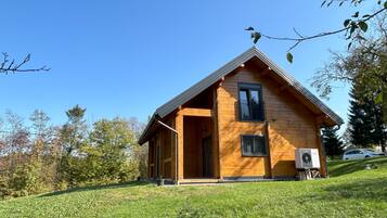 Une cabane en bois avec un toit à deux versants, un balcon et un appareil de climatisation.