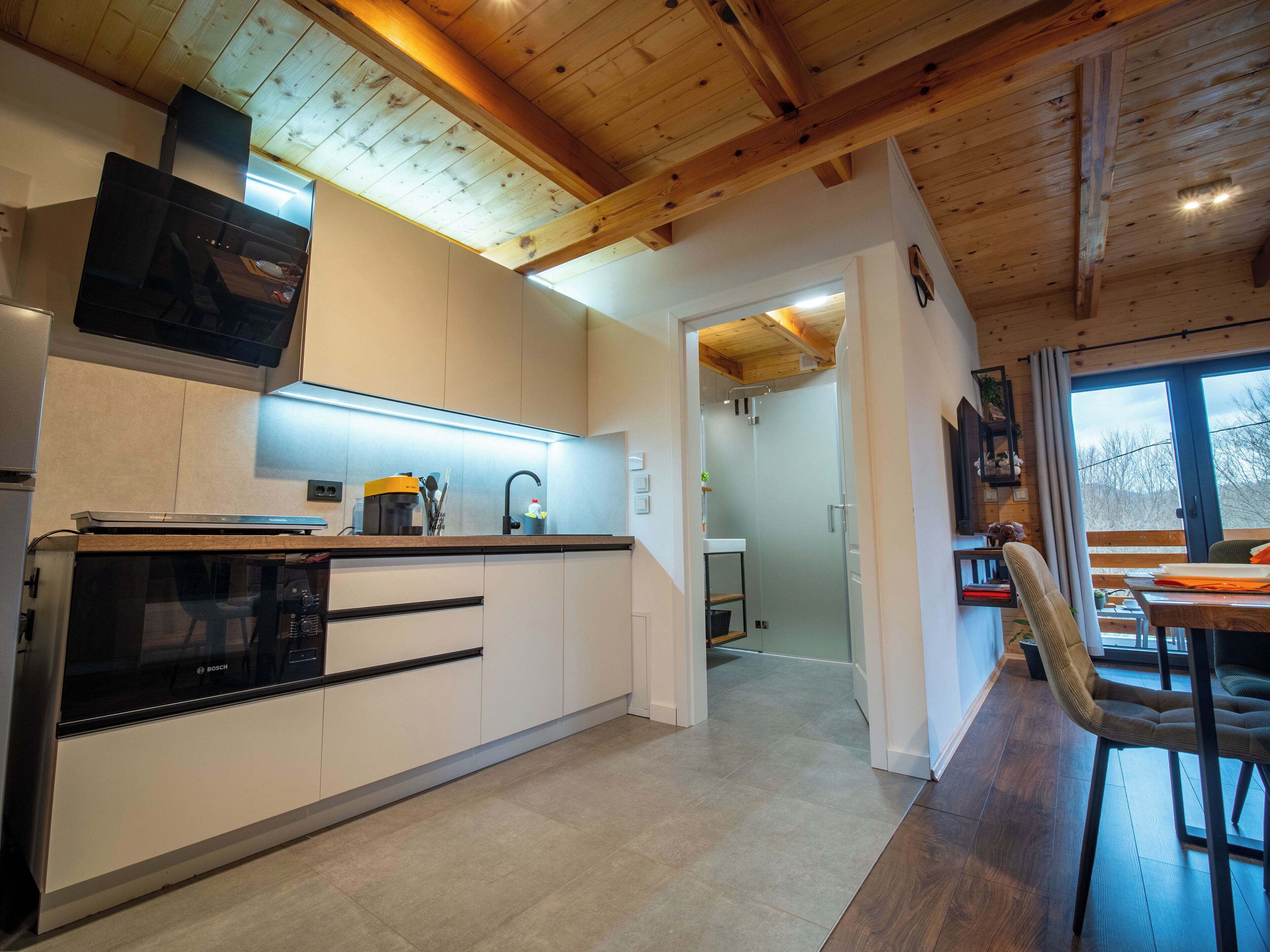 Eine moderne Küche mit Geschirrspüler von Bosch, eingebautem Backofen und Holzboden.