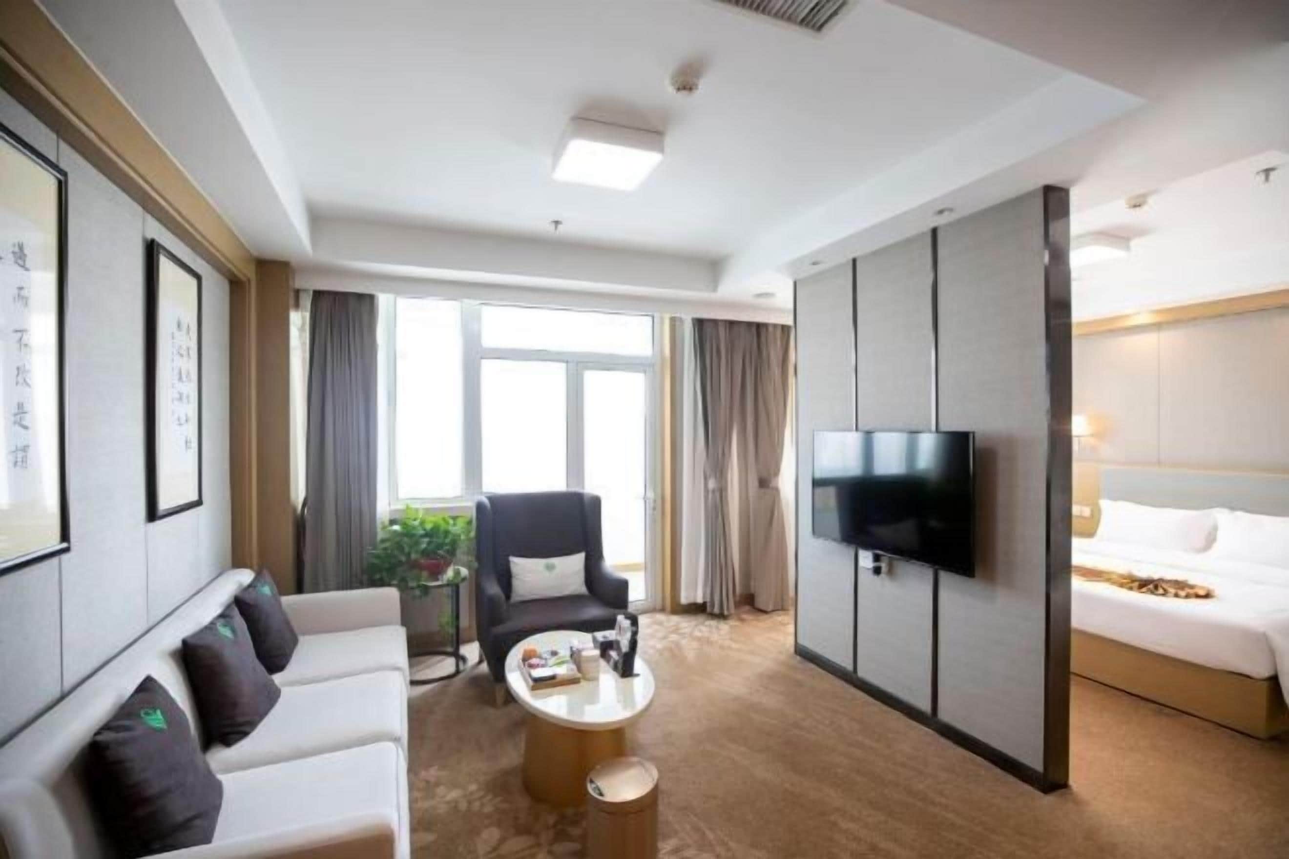 Habitació d'hotel amb sofà, butaca, taula de cafè, televisió i llit.