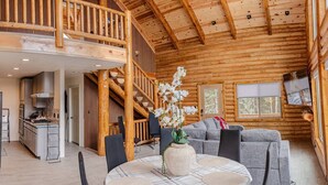 Ein Holzblock-Innenraum mit Essbereich, einer Couch und einer Treppe zu einer oberen Ebene.