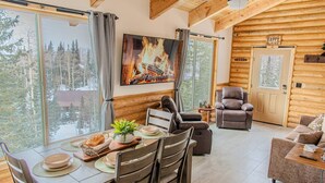 Ein gemütliches Blockhaushaus-Interieur mit Essbereich, Kamin und einer komfortablen Sitzecke.