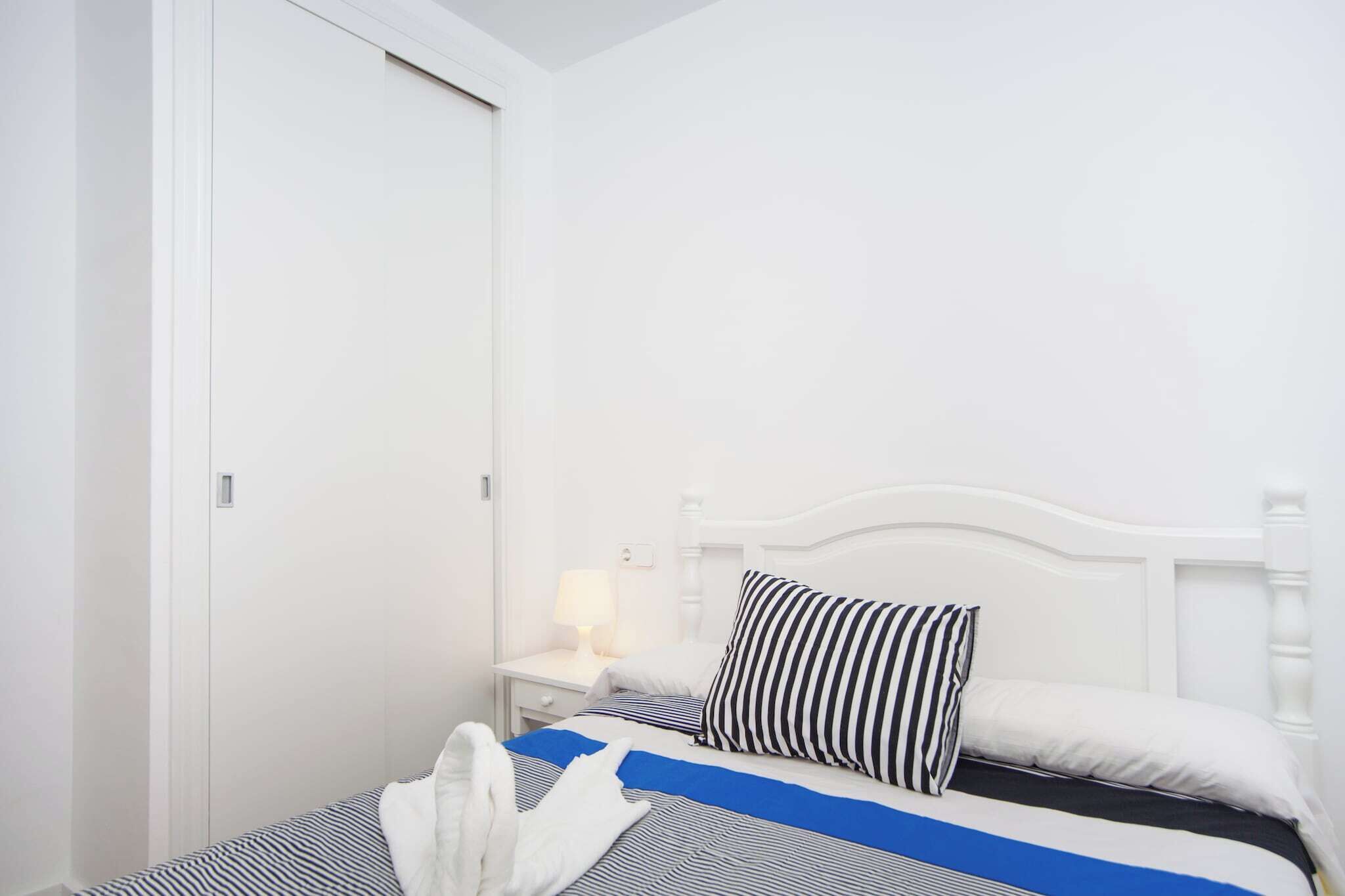 Ein Hotelzimmer mit einem Bett, einem Nachttisch mit Lampe und einem weißen Kleiderschrank.