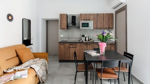 A modern kitchen with wooden cabinets, a microwave, and a dining area with a table and chairs. - Materdei Rooms (Naples)