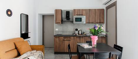 A modern kitchen with wooden cabinets, a microwave, and a dining area with a table and chairs.
