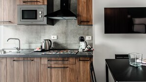 A modern kitchen with wooden cabinets, a built-in microwave, and a black stove. - Materdei Rooms (Naples)
