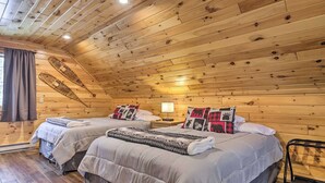 Ein gemütliches Schlafzimmer in einer Holzhütte mit zwei Betten, einem Nachttisch und einer Lampe.
