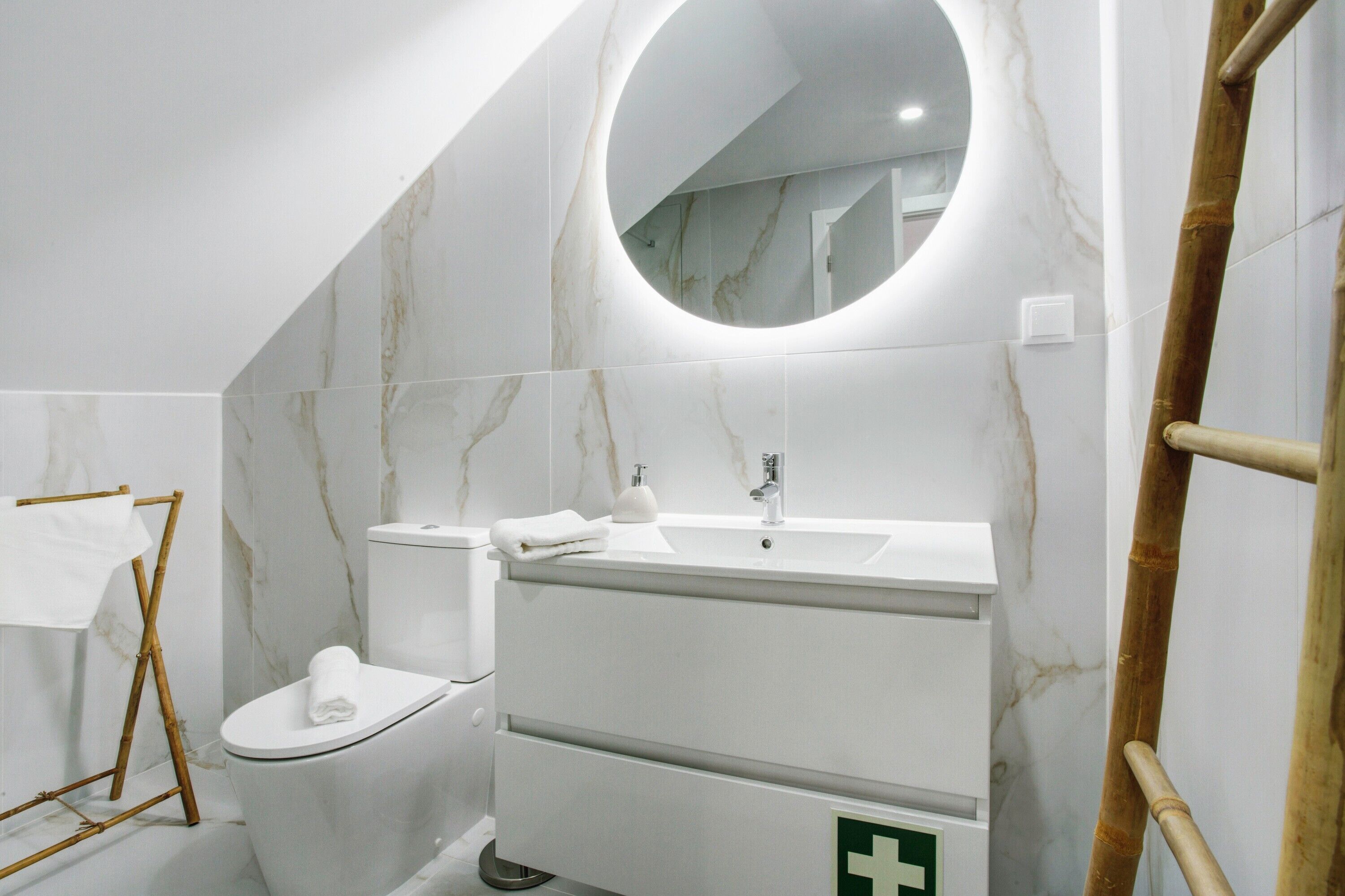 Une salle de bain équipée de toilettes, d’un lavabo, d’un miroir et d’un panneau vert indiquant la sortie de secours.