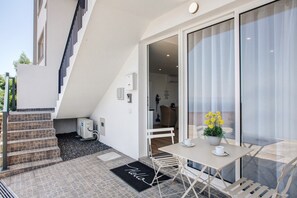 Un appartement moderne doté d’un balcon, d’un coin repas avec une table et des chaises, et d’un escalier menant à l’étage supérieur.