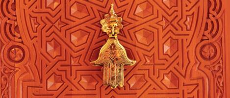 A detailed carved wooden door with geometric patterns and a central golden figure.